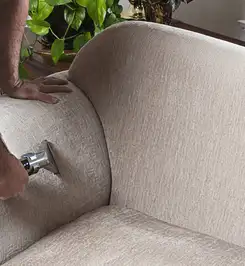 Professional upholstery cleaner deep-cleaning a fabric sofa with a handheld extraction tool and hose {city}, {state}.
